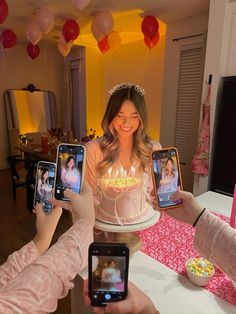 two women holding up their cell phones in front of a cake with candles on it