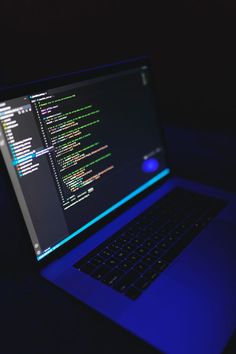 an open laptop computer sitting on top of a dark table in front of a black background