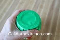 a person holding a green cupcake liner in their hand