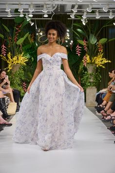 a woman walking down a runway in a white dress