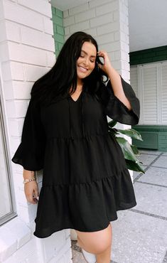 This flirty and flowy black mini dress has a tiered skirt and a tie front detail making it a boho dream! Soft ruffles along the 3/4 sleeves and bottom hem give a feminine touch. Chic V-neck Dress With Ruffle Hem For Day Out, Flowy A-line Brunch Dress, Flowy A-line Dress For Brunch, Chic Flowy Mini Length V-neck Dress, Chic Flowy Mini V-neck Dress, Elegant V-neck Ruffle Dress, Elegant V-neck Ruffle Dress For Casual Occasions, Elegant V-neck Ruffle Dress For Casual Events, Chic Midi Dress With Ruffle Hem For Day Out