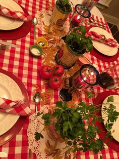 the table is set with red and white checkered cloths, plates, silverware, utensils and tomatoes