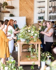 a group of women standing around a table with flowers on it