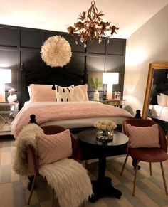 a bedroom with black and white walls, pink bedding, two chairs and a round table