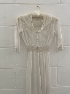 an old white dress hanging on a brick wall