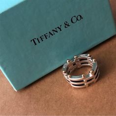 This Elegant And Timeless Gate Link Ring In Fine Sterling Silver With 18k Gold Makes A Worthy Addition To Any Jewelry Collection. Made By Tiffany & Co., Its Flawless Craftsmanship And Design Perfection Features A Collapsible Gate Link Design. The Artfully Design Gold Hinge Details Yet Amplify Its Incredibly Detail Precision. Details Type: Ring Design: Gate Link Size: 5.5 Metals: Sterling Silver/18k Gold Total Weight: 11.5g Marks: Tiffany & Co. 925 750 Condition: Pre-Owned/Good Designer White Gold Ring In Sterling Silver, Aaa Quality White Gold Sterling Silver Rings, Designer White Gold Rings For Everyday Luxury, Designer White Gold Rings For Gift, High-end White Gold Jewelry For Anniversary, Designer White Gold Jewelry, Collapsible Gate, Link Ring, Link Design