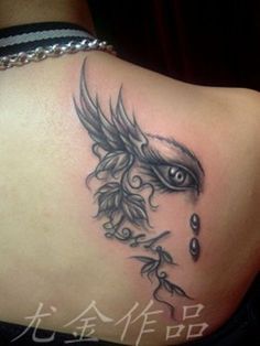 the back of a woman's shoulder with an evil eye and leaves on it