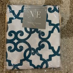 a white and blue patterned sheet set on the floor next to a package of toilet paper