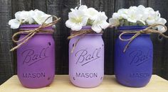 three painted mason jars with flowers in them