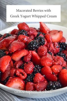 a white bowl filled with sliced strawberries and blueberries on top of a table