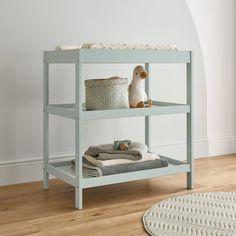 a baby changing table with a stuffed animal on it's back and some blankets underneath