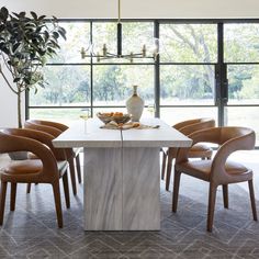 a dining room table with chairs around it and a vase sitting on top of the table