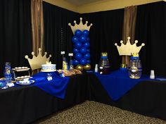 a table topped with blue and gold desserts next to black drapes covered walls