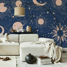 a dog sitting on top of a white couch in front of a blue wall with sun and moon designs