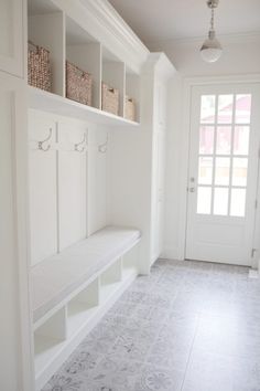 a white entryway with shelves and baskets on the wall