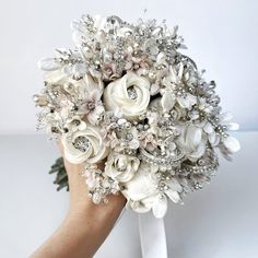 a bridal bouquet is being held by someone's hand on a white surface