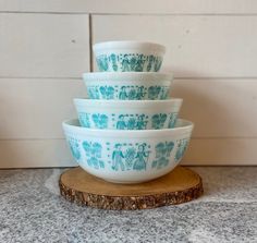 four blue and white bowls stacked on top of each other in front of a wall