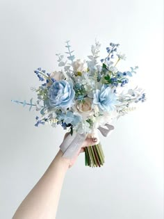 a hand holding a bouquet of blue and white flowers