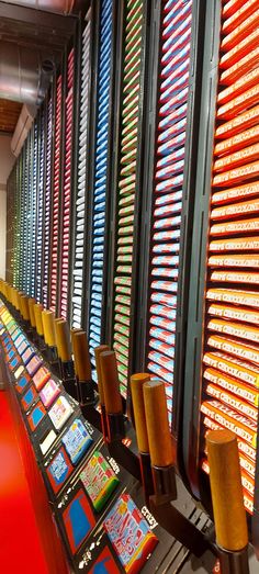 rows of brightly colored candy machines lined up against a wall in a room with red carpeting