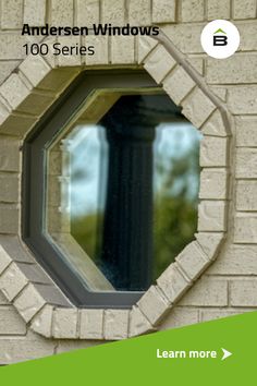 an image of a round window on the side of a brick building with green trim