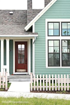 a blue house with white picket fence around it and a red door on the front