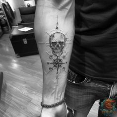 a man with a skull and compass tattoo on his arm