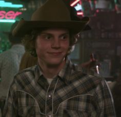 a young man wearing a cowboy hat in a bar