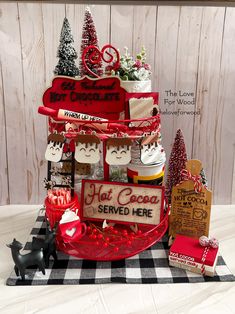 a christmas display with cupcakes, cookies and other treats on it in front of a wooden wall