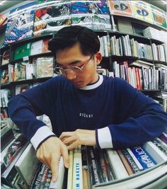 a man is looking at some books in a bookstore shelf with his hands on the shelves