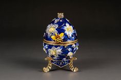 an ornate blue and gold egg with flowers on it