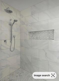 a bathroom with white marble and hexagonal tiles on the shower wall, along with a chrome faucet