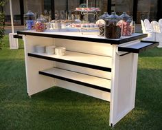 a buffet table with plates and cups on it in the middle of some green grass