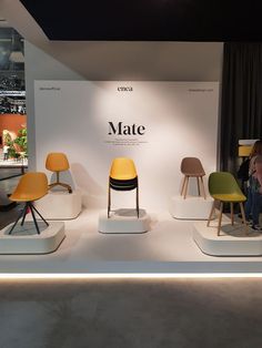 several chairs are on display in front of a white wall with the word mate written on it