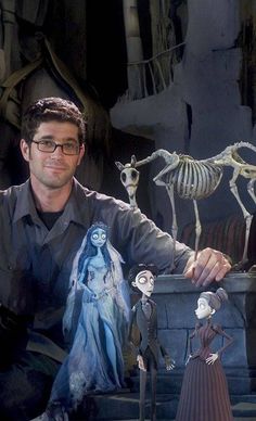 a man sitting in front of some fake skeletons