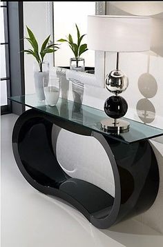 a black and white console table with vases on the top, next to a lamp