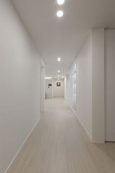 an empty room with white walls and wood floors is seen in this image from the hallway