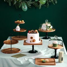 a table topped with cakes and desserts on top of wooden trays next to green balloons