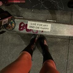 a person standing next to a sign that says live for art and die happy