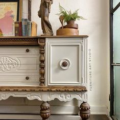 an old dresser with a statue on top and bookshelf in the back ground