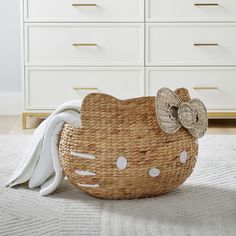 a wicker basket with a hello kitty bow on it sitting on the floor in front of a dresser