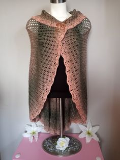 a crocheted shawl on a mannequin with flowers in the background