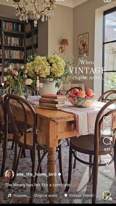 an image of a dining room table with flowers and fruit on it, surrounded by bookshelves