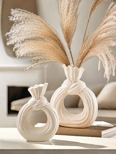 two white vases sitting on top of a table