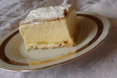 a piece of cheesecake on a plate with powdered sugar and gold trim around the edges