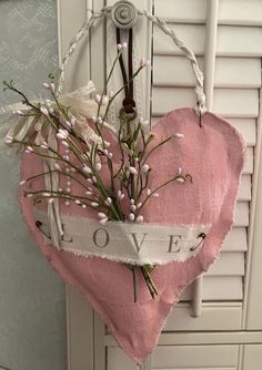 a heart hanging on the wall with flowers in it