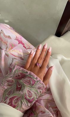 a woman's hand with pink manicures on top of a white cloth