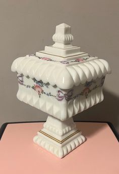 a white vase sitting on top of a pink table