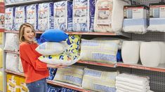 a woman is holding pillows in a store