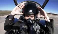 a man in a pilot's helmet and goggles holds his hands up to his face