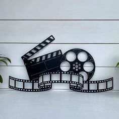 a black and white photo of a film reel with a plant in the foreground